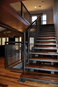 The Banker Wire mesh and U-edge frame harmonize visually with the weathered steel railing and reclaimed barn wood stair treads
